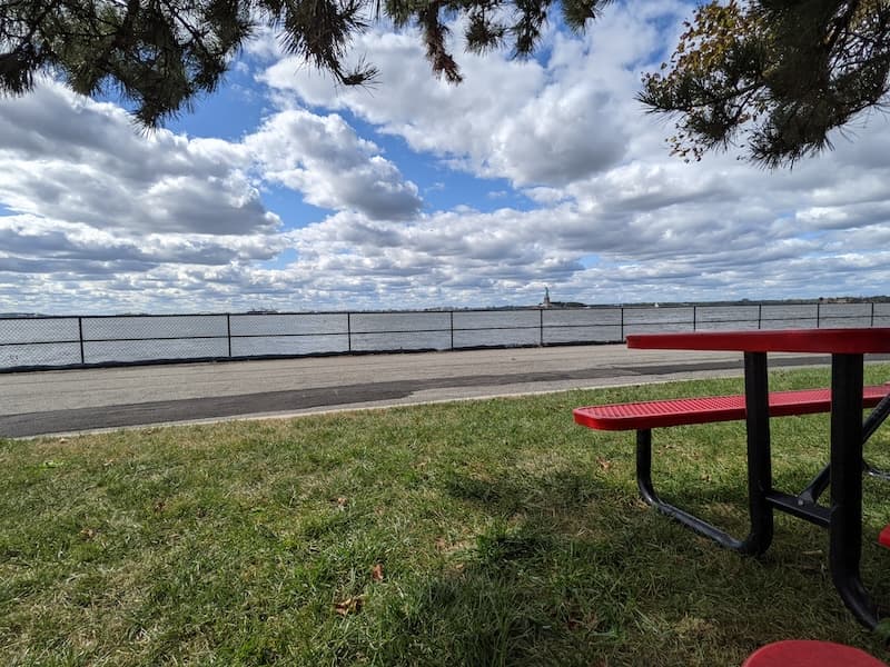 Red picnic table on Governors Island with the Statue of Liberty across the water